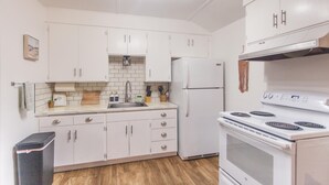 Una cocina moderna con armarios blancos, un lavamanos de acero inoxidable, horno empotrado y refrigerador.