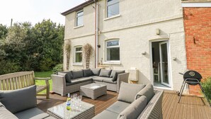A patio with outdoor furniture, a barbecue grill, and a house with a brick section. - Morningside (Totland Bay)