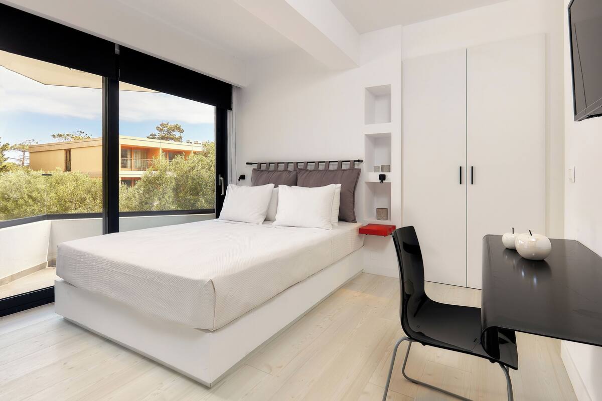 Un dormitorio moderno con cama, escritorio y televisor.