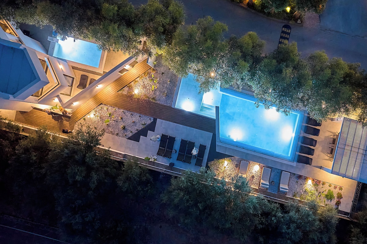 Un espace piscine extérieur moderne comprenant une piscine rectangulaire, une terrasse en bois et des coins salon.