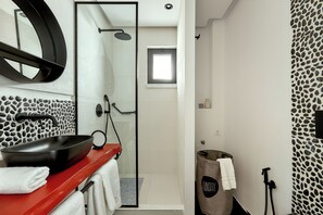 Enjoy a refreshing shower in the bathroom, featuring a sleek basin, large mirror, and glass-enclosed shower with handheld showerhead.
