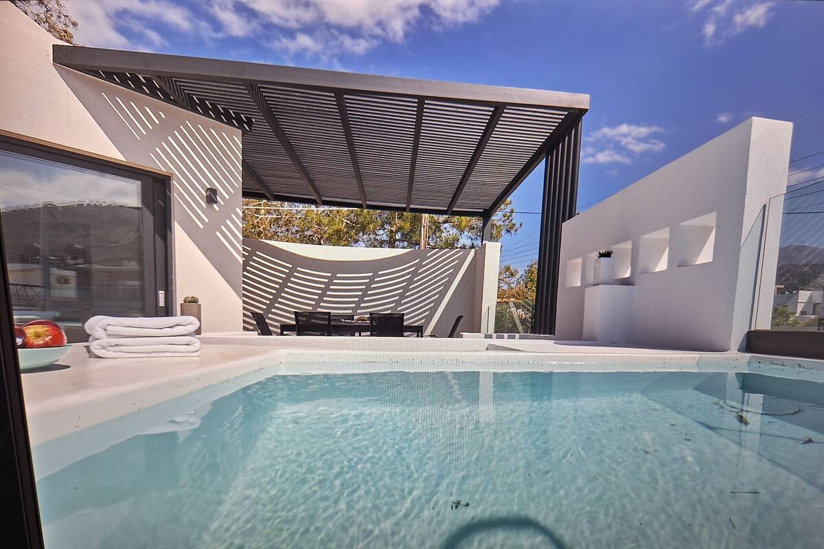 Un área de piscina moderna con una piscina cristalina, una zona de estar cubierta y vistas del paisaje circundante.