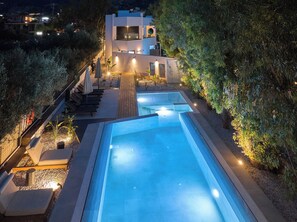 Relax by the rectangular pool surrounded by lush greenery and lounge chairs.