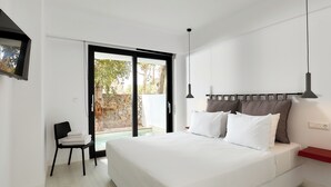Quarto com uma cama grande, uma cadeira, uma estante vermelha e uma porta de vidro deslizante que dá para uma área externa.