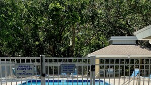 A private pool with a fenced area, a wooden deck, and a sign indicating ID tags are required for use between 8 am and 9 pm.