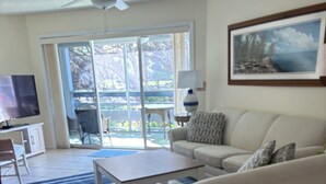 A living room with a sofa, coffee table, TV, and a painting on the wall.