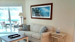 A living room with a sofa, a coffee table, a small table, and a framed picture on the wall.