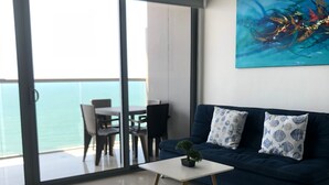 Un salon moderne avec un canapé bleu foncé, une table basse blanche et un tableau accroché au mur.