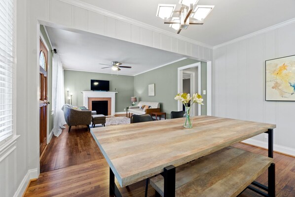 A dining area with a wooden table, chairs, and a vase of flowers.
