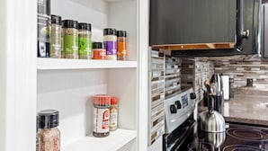 Een keuken met een fornuis, oven en planken met diverse kruiden.