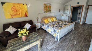 A bedroom with a bed, a nightstand, a dresser, a ceiling fan, and a large window.