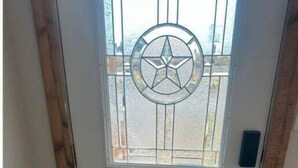 A white door with a star-shaped glass window, a doormat with the word "sunshine", and a wooden floor.