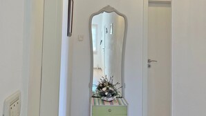 Een gang met een groene dressoir, een spiegel en een hangende lamp.