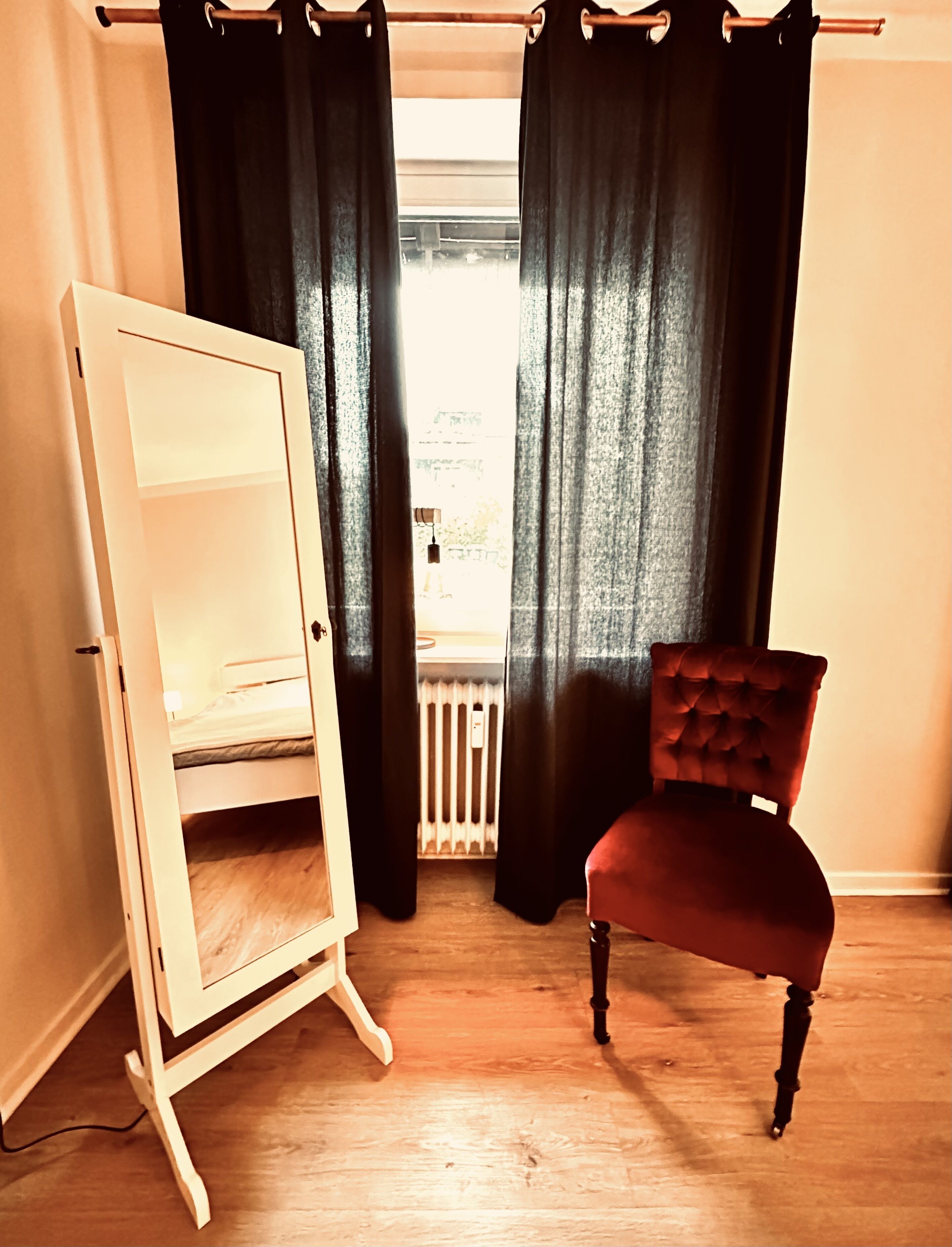 Ein Zimmer mit einem Bett, einem roten Sessel und einem weißen Kleiderschrank.