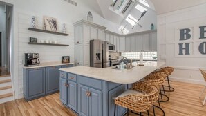 Una cocina moderna con armarios azules, una isla grande, taburetes de bar y un tragaluz.
