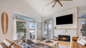 Un salón amplio con chimenea, sofás de cuero, televisor y ventilador de techo.