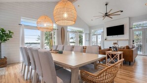 Una habitación amplia con una gran mesa de comedor, sillas de mimbre, un sofá y un ventilador de techo.