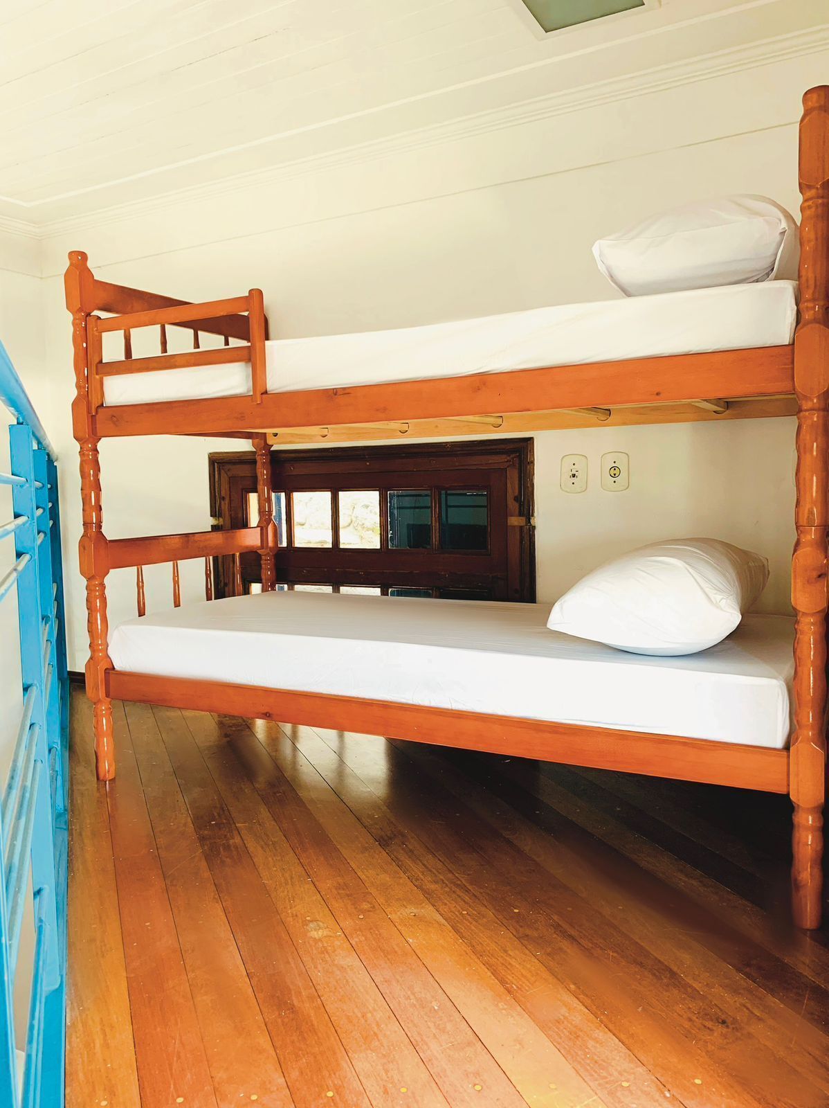 Una cama litera con estructura de madera y ropa de cama blanca.