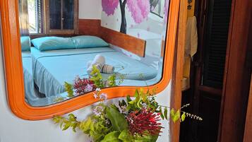 Un dormitori amb un llit, un mirall, un ram de flors i una paret amb un mural d'un arbre.
