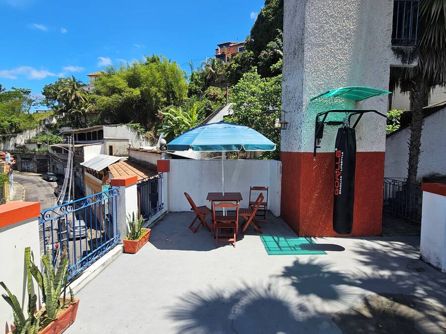 An outdoor patio area with a table and chairs, a green umbrella, and potted plants.