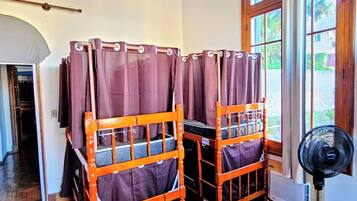 A room with wooden bunk beds, a ceiling fan, and a window with curtains.