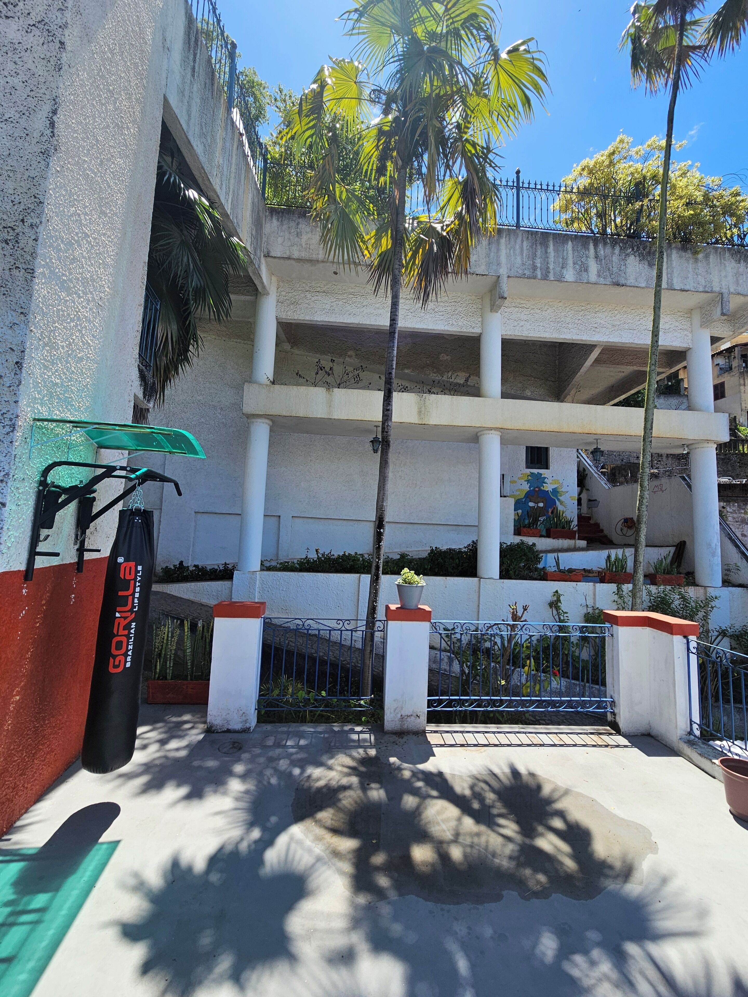 A building with multiple balconies, palm trees, and a green exercise bike.