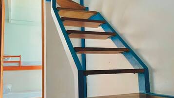 A wooden staircase with blue railings leading to a room with bunk beds.