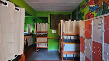 Une chambre de dortoir avec des lits superposés, un ventilateur et des casiers.