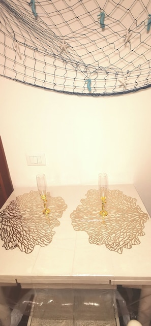 A table with two glasses of champagne, a decorative metal mesh ceiling, and a white wall. - The Rocks a Stone's Throw Away (Portovenere)