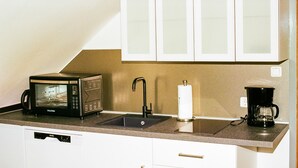 Een kitchenette met een magnetron, spoelbak en koffiezetapparaat.