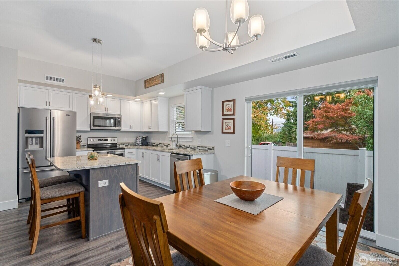 A modern kitchen with white cabinetry, stainless steel appliances, and a large island with seating.