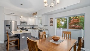 A modern kitchen with white cabinetry, stainless steel appliances, and a large island with seating. - New 2 BR Townhouse in the Heart of Wenatchee. Great for Families, pet friendly. (Wenatchee)