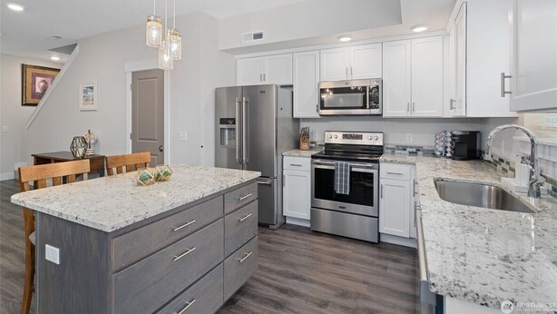 A modern kitchen with white cabinets, stainless steel appliances, and a granite countertop. - New 2 BR Townhouse in the Heart of Wenatchee. Great for Families, pet friendly. (Wenatchee)
