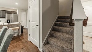 A staircase with carpeted steps and a white handrail, leading to a room with a white door. - •Lamine Elegance Drive• FreeWine, GameRoom & HotTub (Colorado Springs)