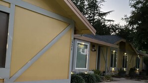 A yellow building with a large window and a door, surrounded by a well-maintained lawn and trees. - Cozy 5BR Ranch Home with Hot Tub in Quiet Folsom Neighborhood (Folsom)
