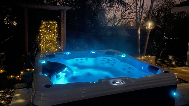 A hot tub with a control panel, surrounded by a patio area with a Christmas tree and string lights. - Cozy 5BR Ranch Home with Hot Tub in Quiet Folsom Neighborhood (Folsom)