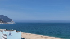 A coastal view with a beach, ocean, and a building with a logo.
