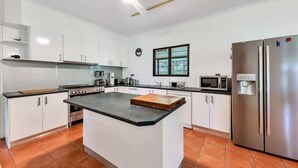 A modern kitchen with white cabinets, a central island, stainless steel appliances, and a window providing natural light.