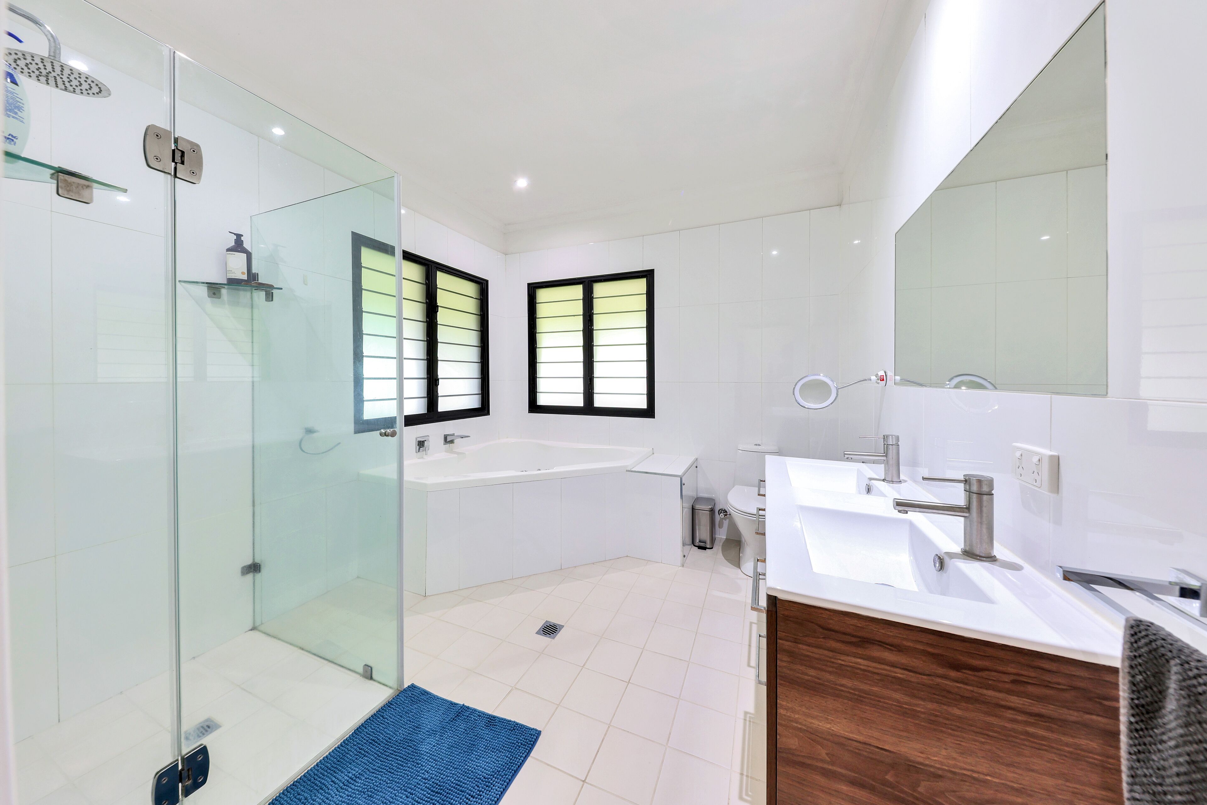 Een moderne badkamer met een glazen douchecabine, een ruim bad en een wastafel met spiegel.