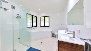 A modern bathroom with a glass shower enclosure, a large bathtub, and a vanity with a mirror. - Riverside Homestead (Darwin River)
