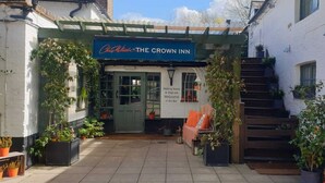 A courtyard with a sign for "Chris White's at The Crown Inn" and a welcoming message. - The Crown Inn at Burnham Beeches (Slough)