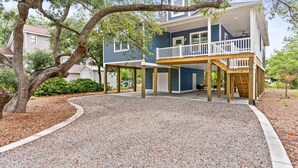 A two-story house with a covered patio area and a gravel driveway.