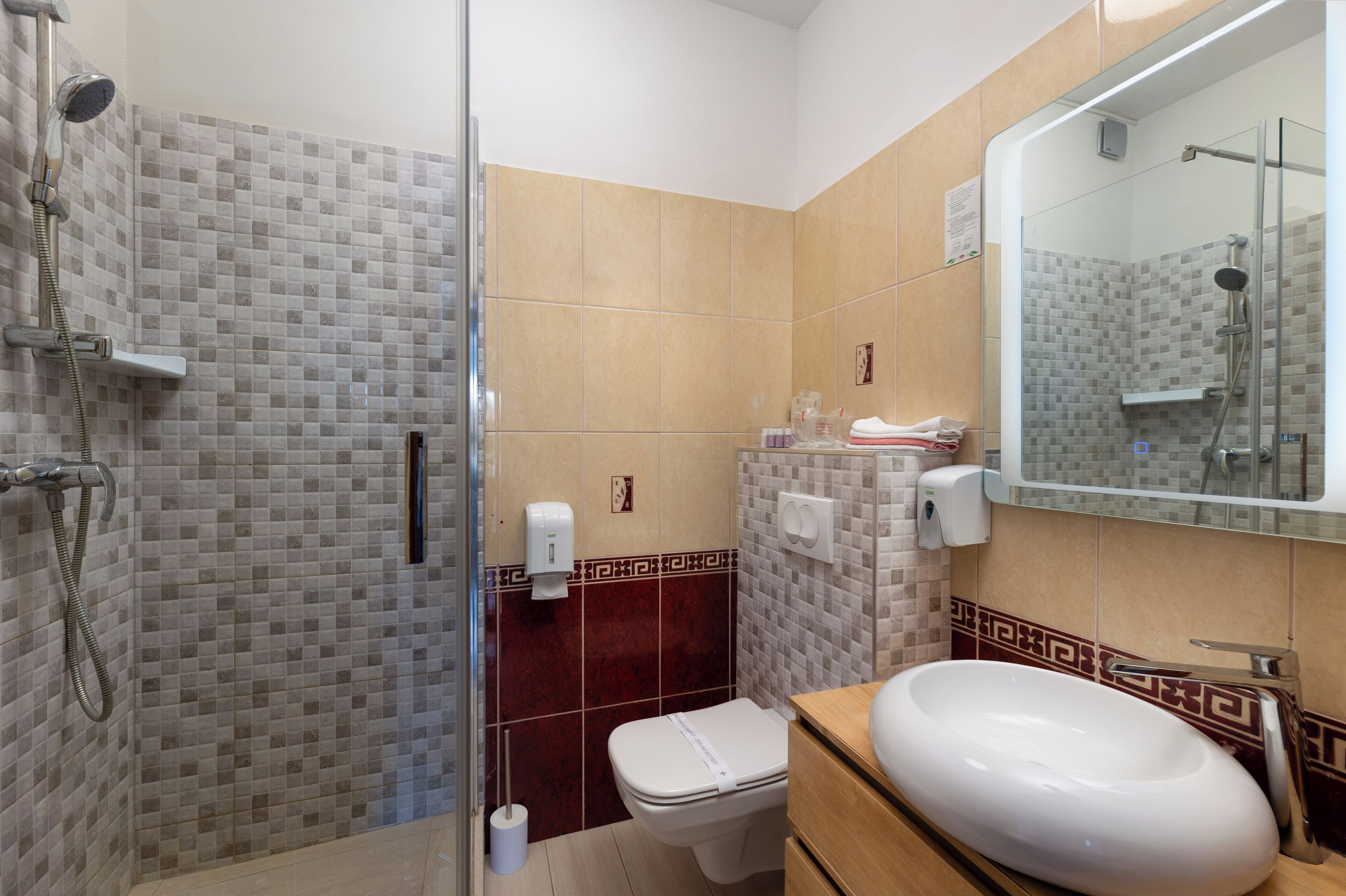 A bathroom with a glass-enclosed shower, a toilet, and a sink with a mirror above it.