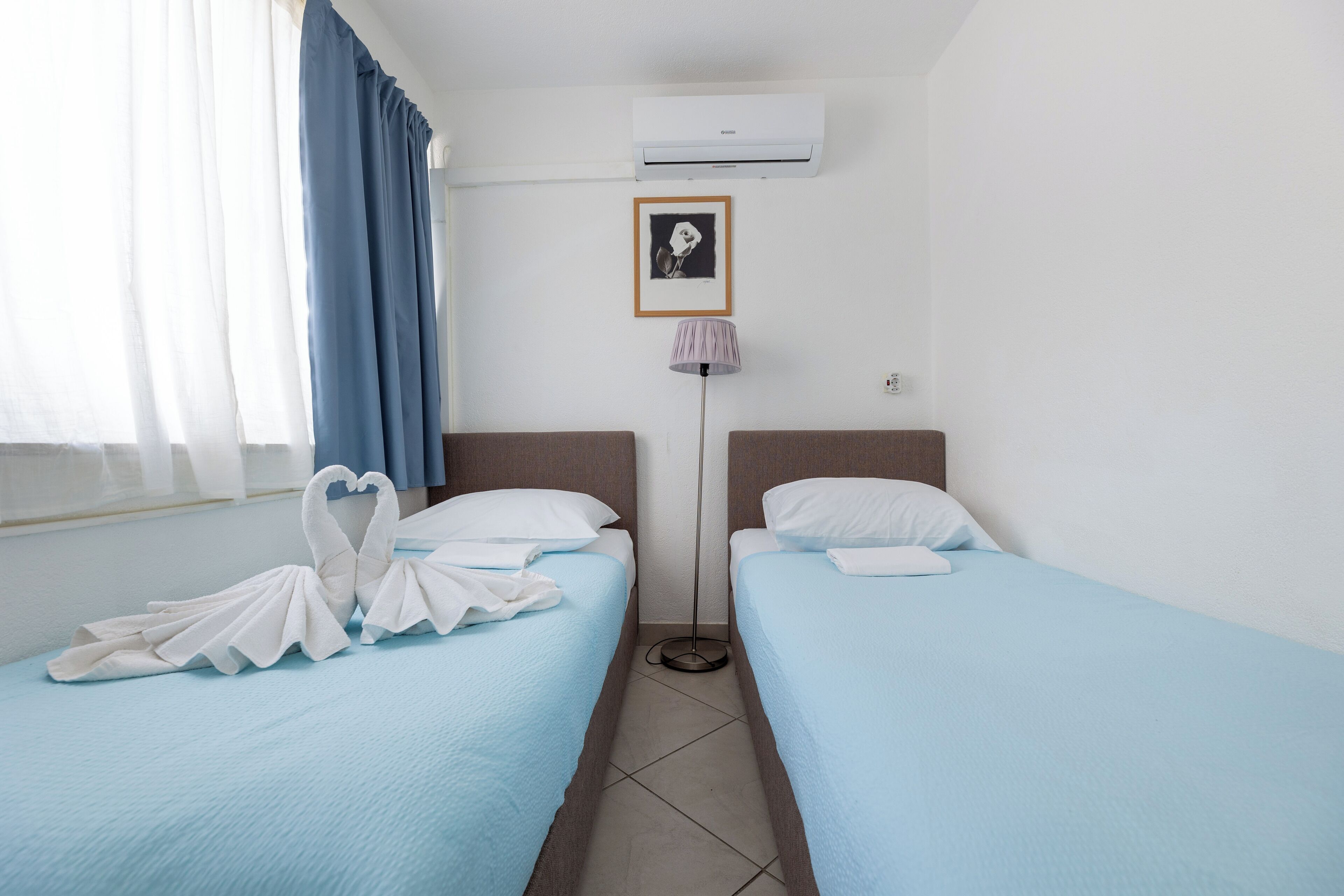 Una habitación de hotel con dos camas, una lámpara de pie y un cuadro en la pared.
