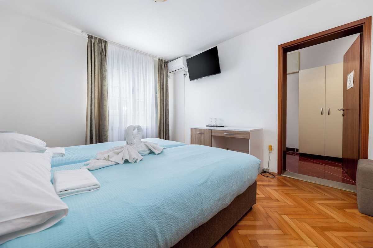 A hotel room with a bed, a desk, a TV, and a wardrobe.