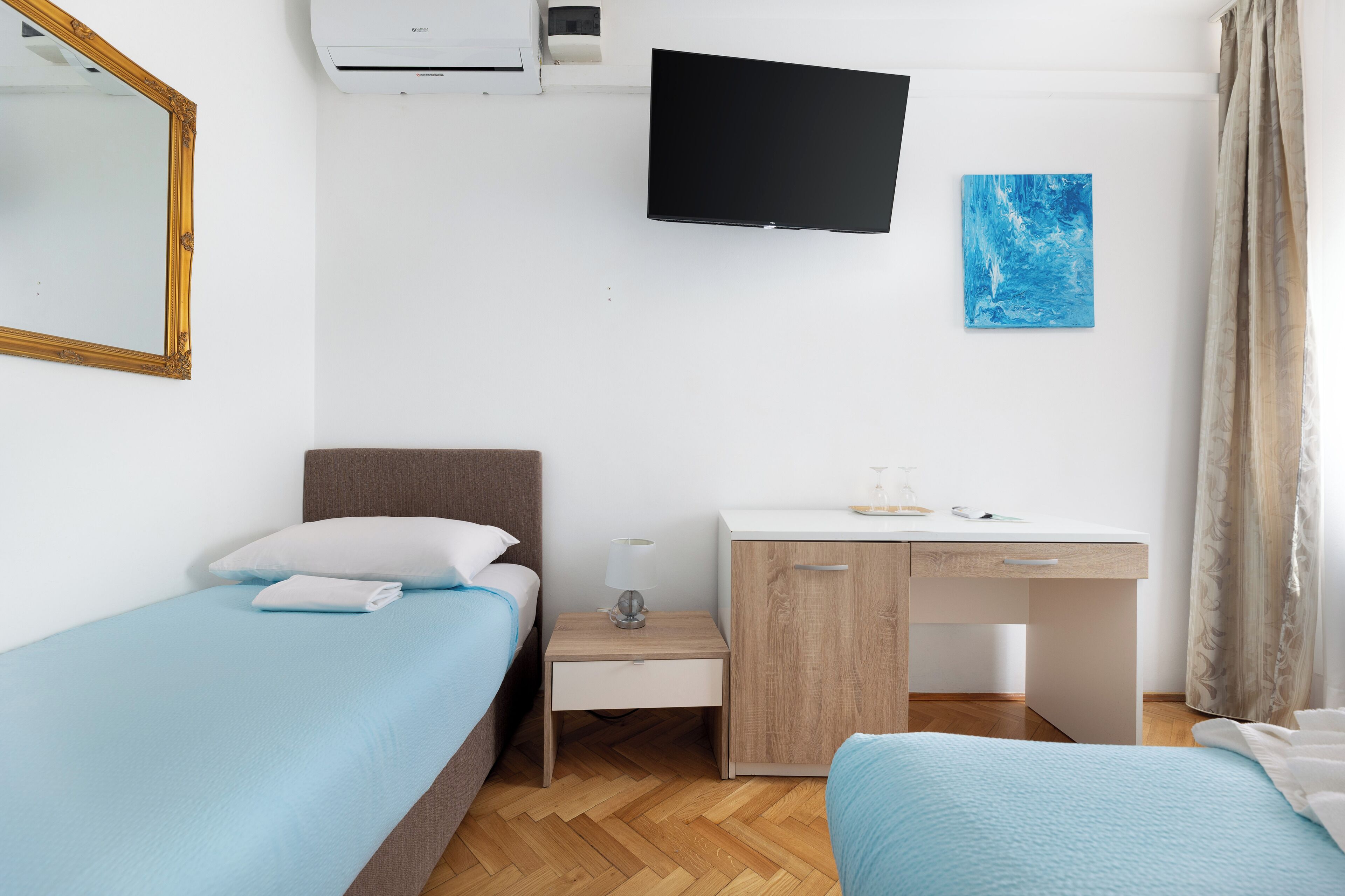 Habitación de hotel con cama, escritorio, silla, televisor de pantalla plana y ventana con cortinas.
