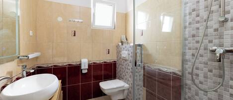 A bathroom with a large oval sink, a toilet, and a glass-enclosed shower area.