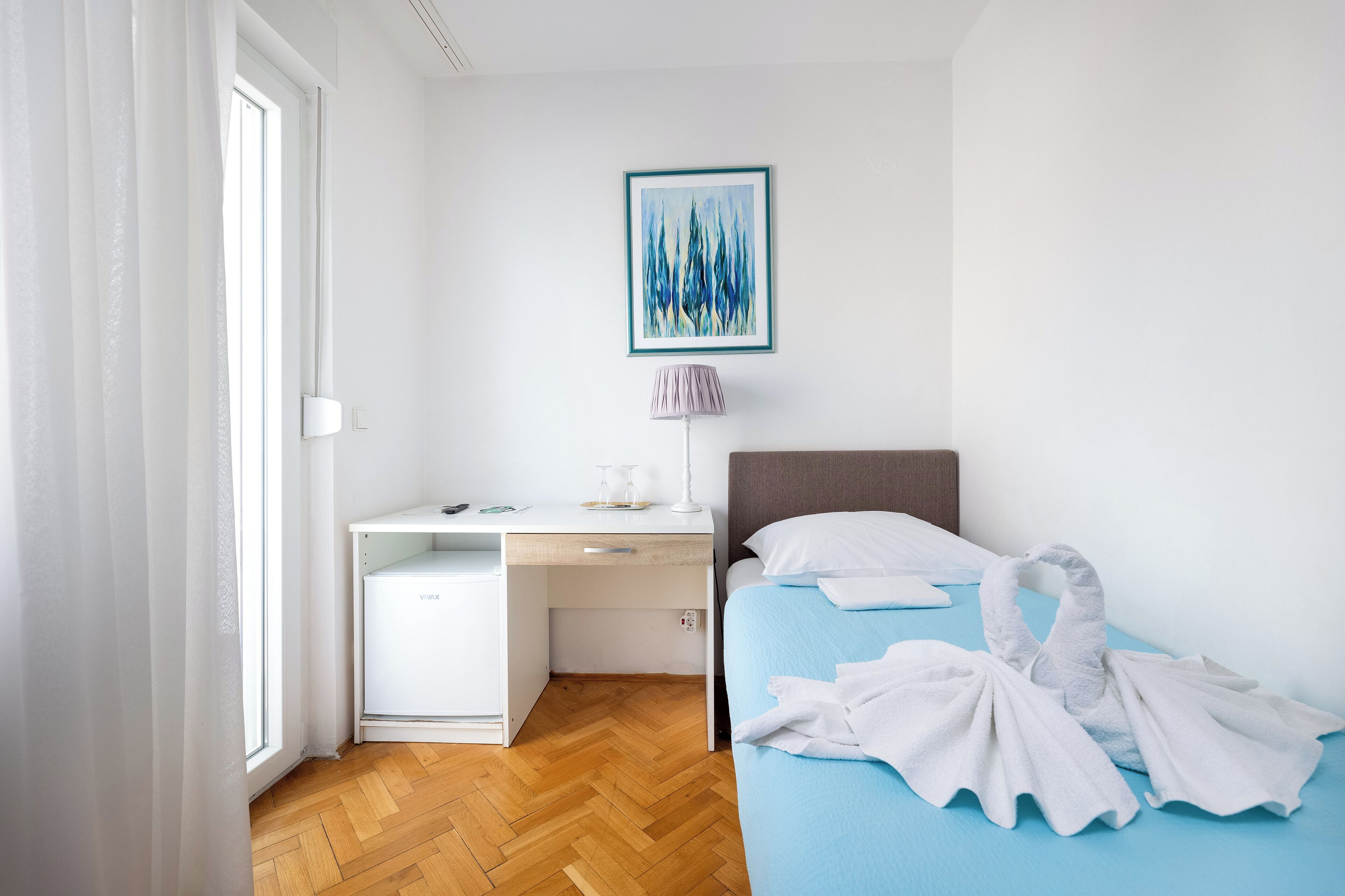 A bedroom with a bed, a desk, and a chair.