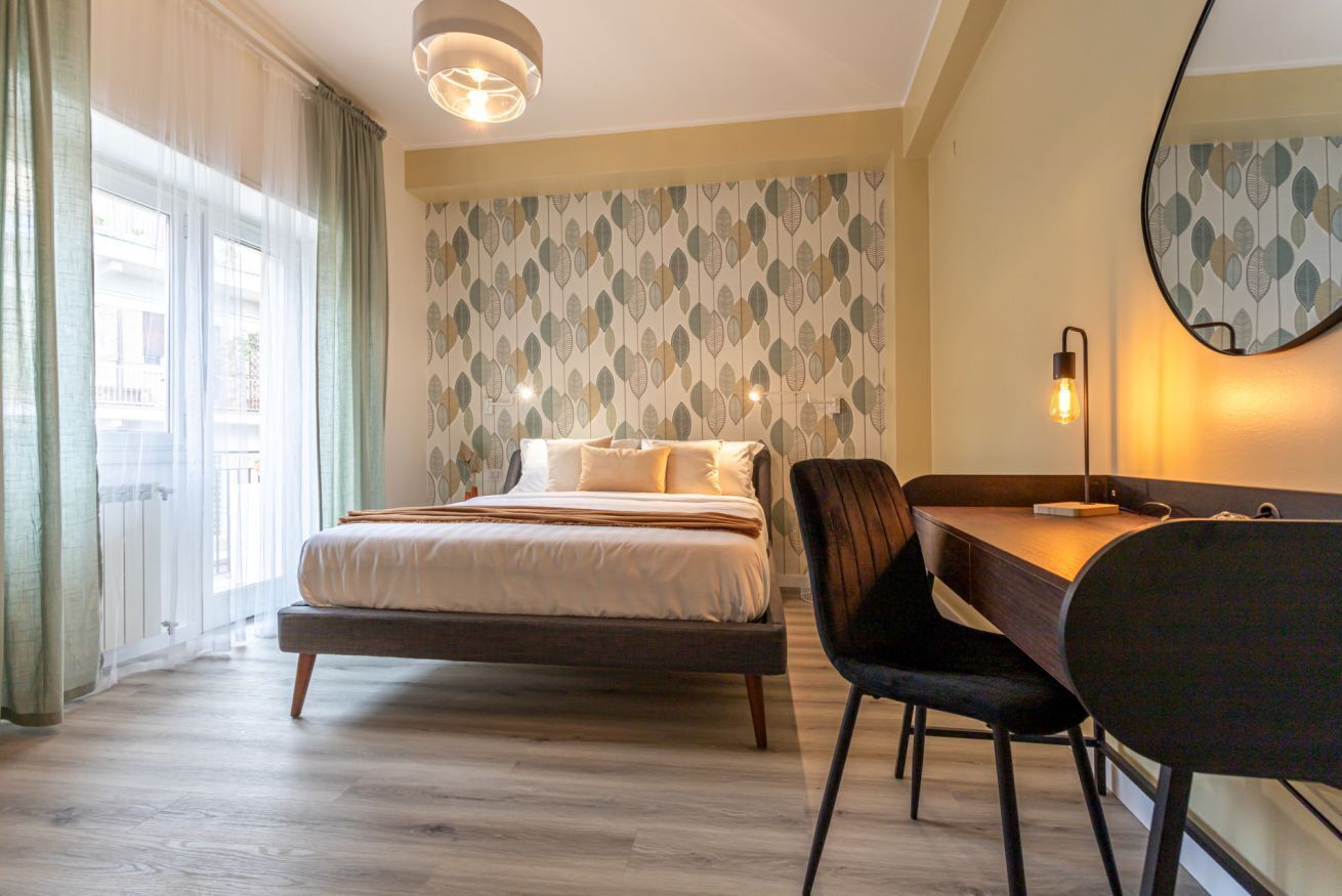 A bedroom with a bed, bedside table, and a desk with a chair.