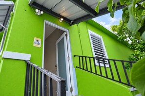 Un edificio verde brillante con una puerta, una ventana con contraventanas y un letrero de advertencia de seguridad.